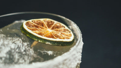 Close-up of a cocktail glass garnished with a dehydrated lime wheel and an edible flower, showcasing the Garnish & Graze collection
